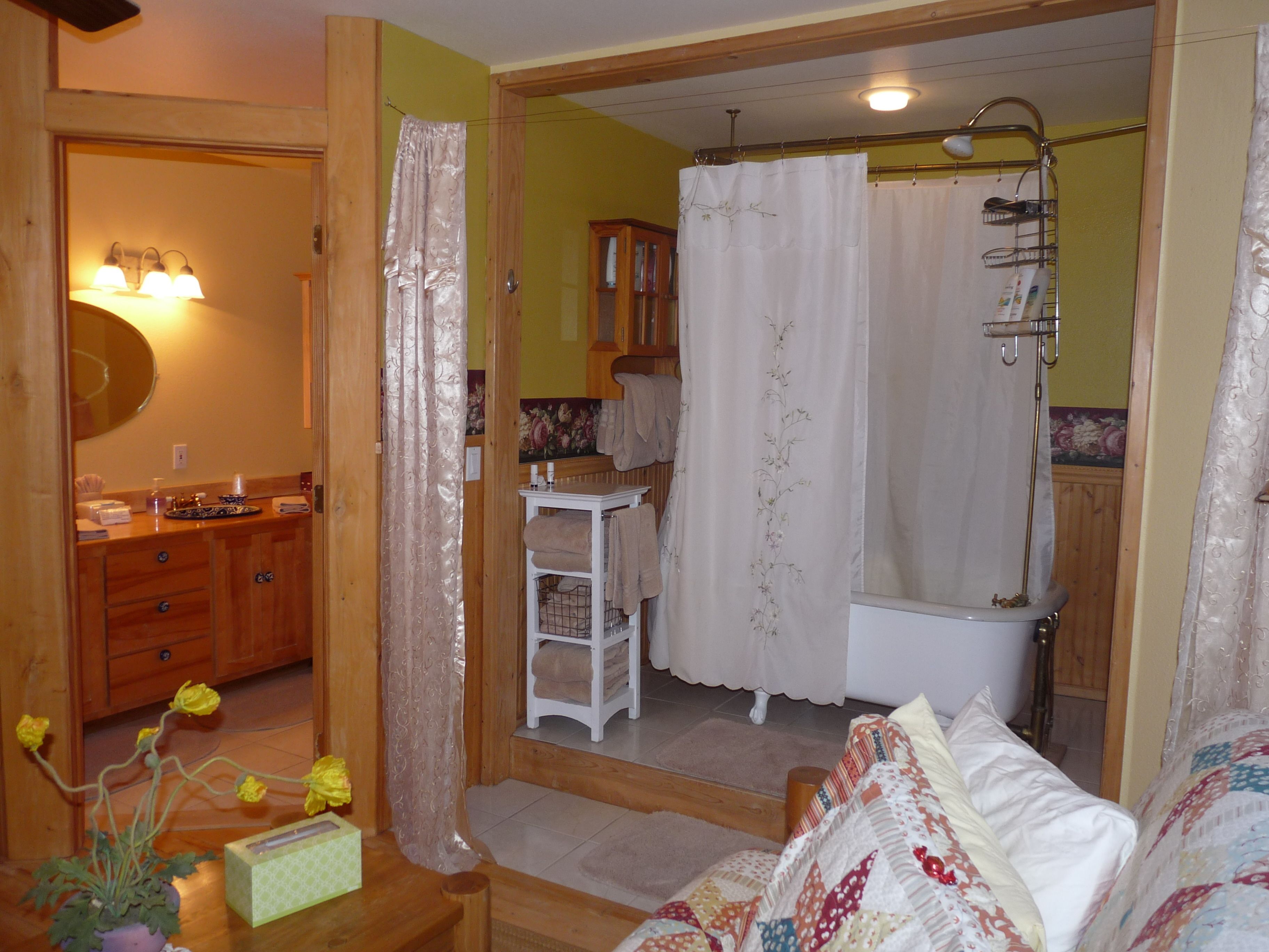 A bathroom with a bathtub, shower, and a wooden vanity with a mirror.