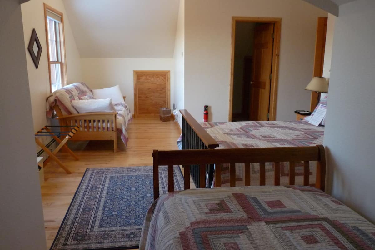 Um quarto com uma cama, uma cadeira de madeira, uma mesa e um tapete estampado.