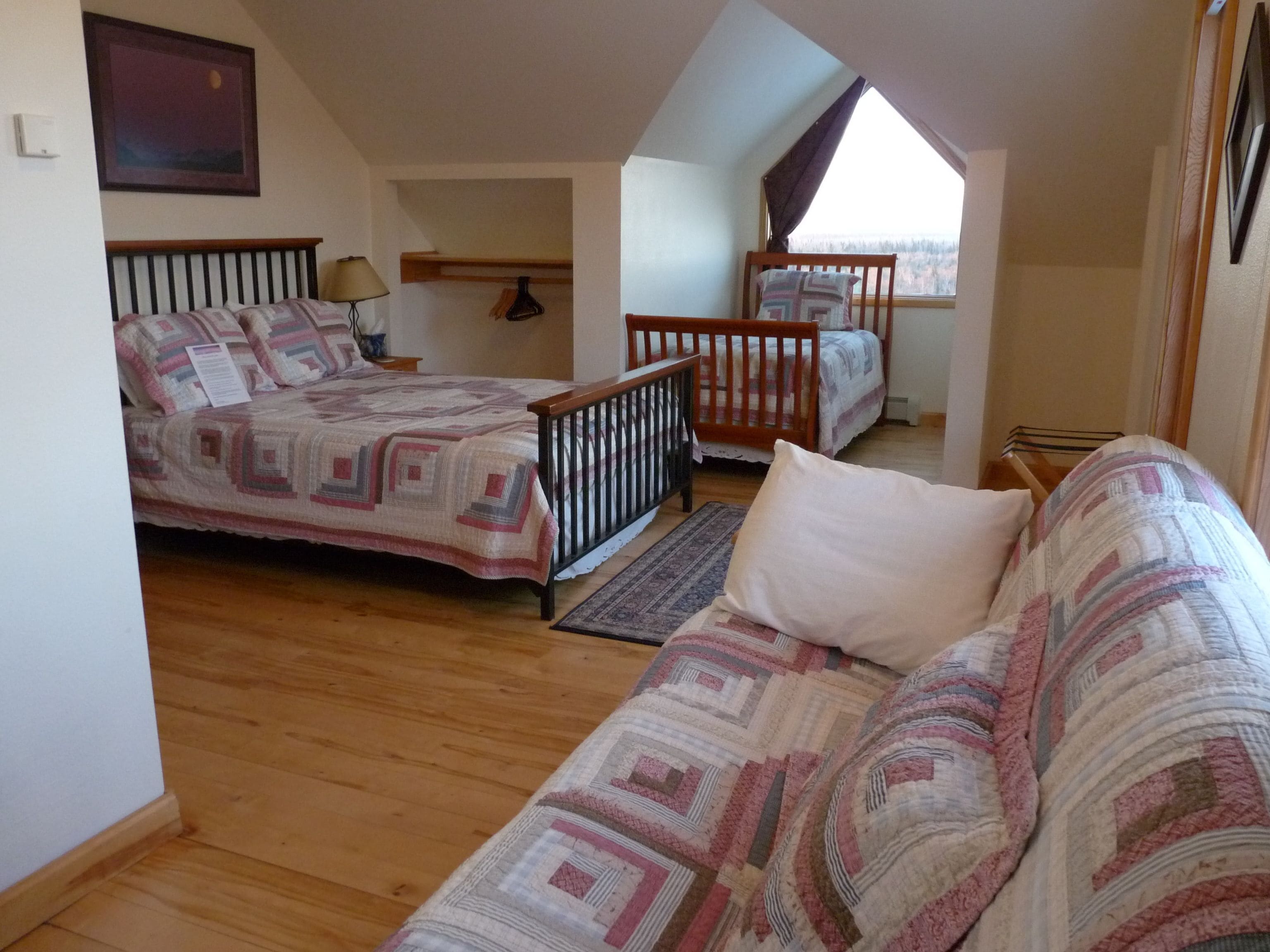 Un dormitorio con dos camas, suelo de madera y techo inclinado.