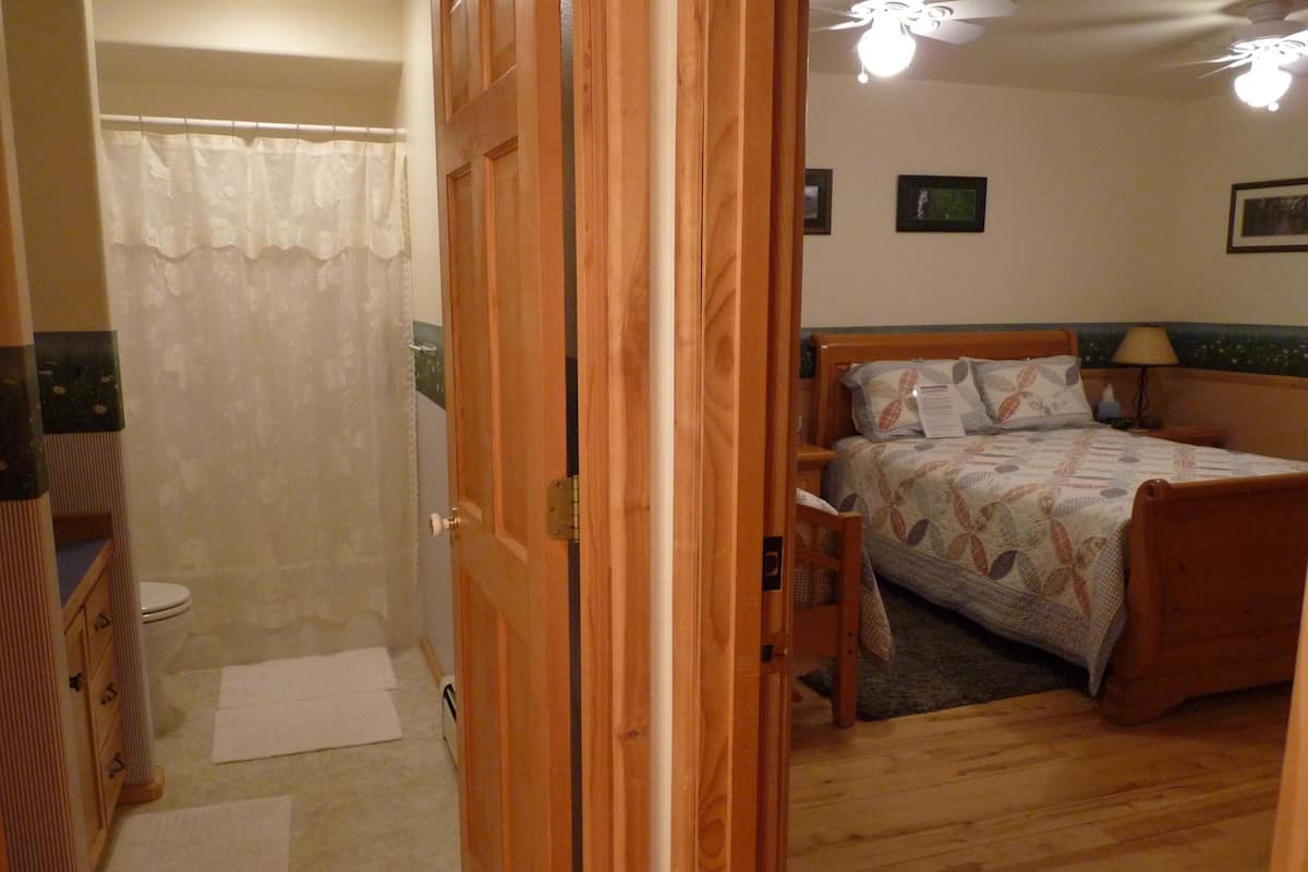 Quarto com cama de madeira, mesa de cabeceira, abajur e ventilador de teto.