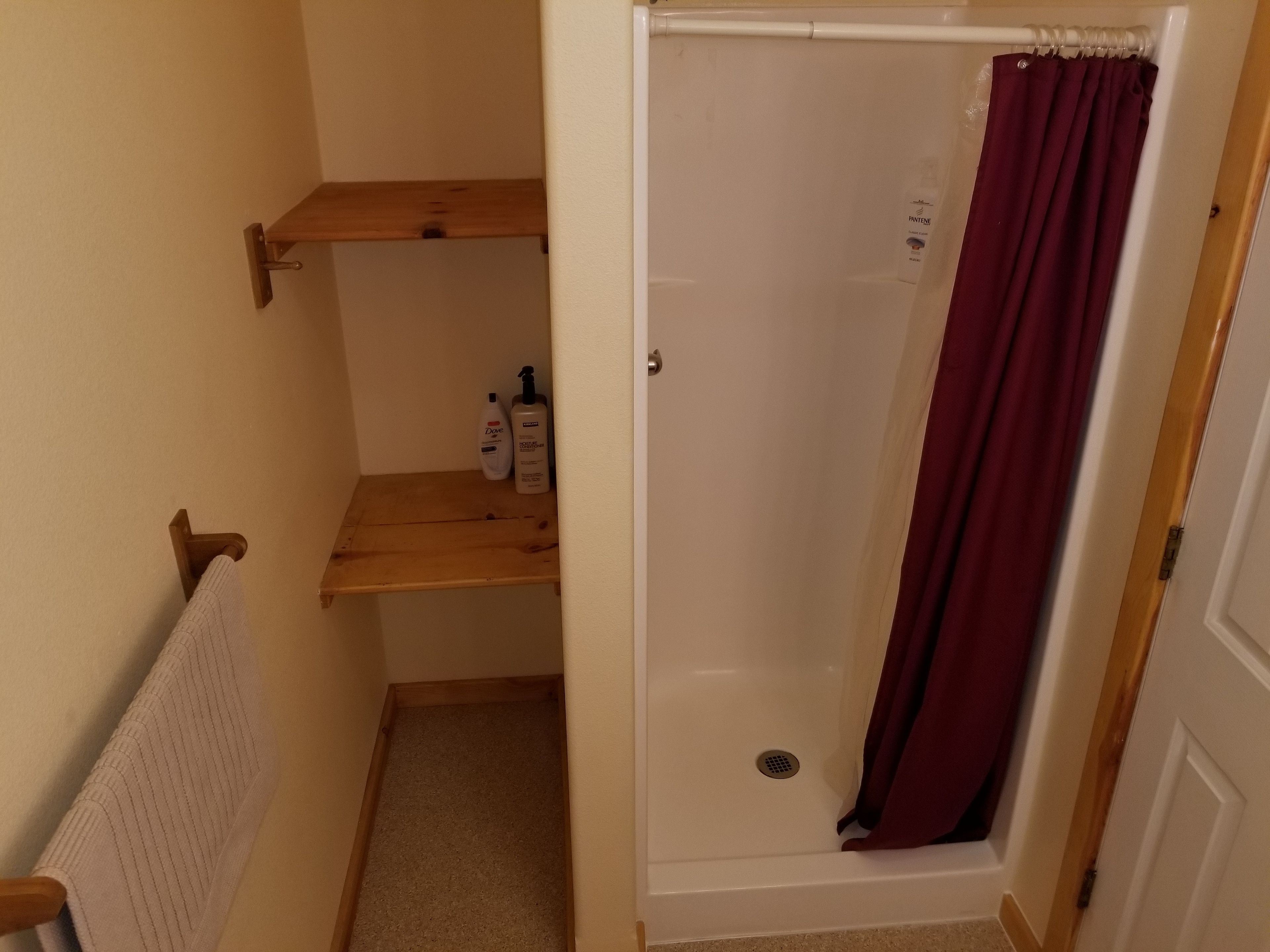 Ein Badezimmer mit Dusche, Ablage für Toilettenartikel und Handtuchhalter.
