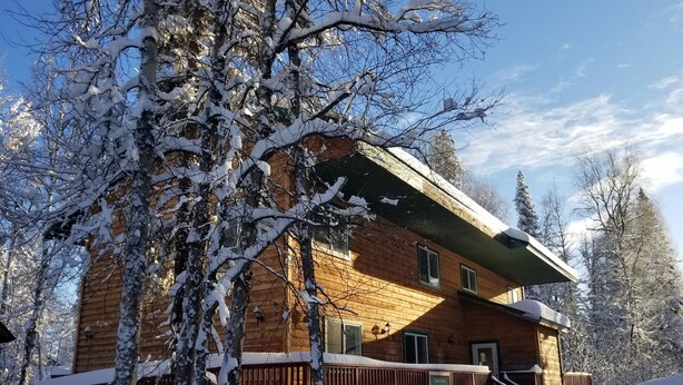 En træhytte med en overdækket veranda og et skilt, der viser, at det er et gæstehus.