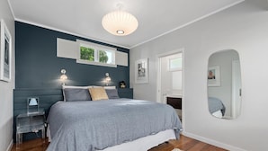 Un dormitorio con cama, lámparas de noche, mesita de noche, espejo y ventana.