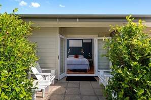 A bedroom with a bed, a nightstand, and a window with curtains. - Devonport Motel (Auckland)