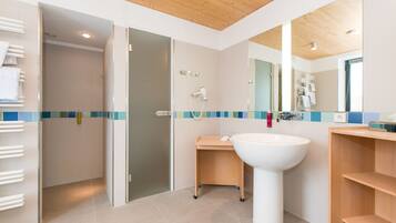 Un baño moderno con techo de madera, un lavamanos grande, un espejo y una zona de ducha.