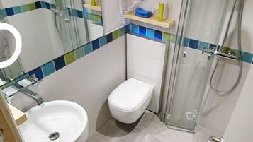 A bathroom with a white sink, a toilet, and a glass shower enclosure.