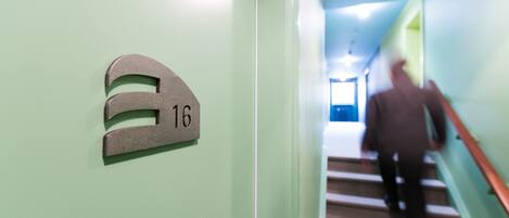 A hallway with a green wall and a sign indicating room number 16.