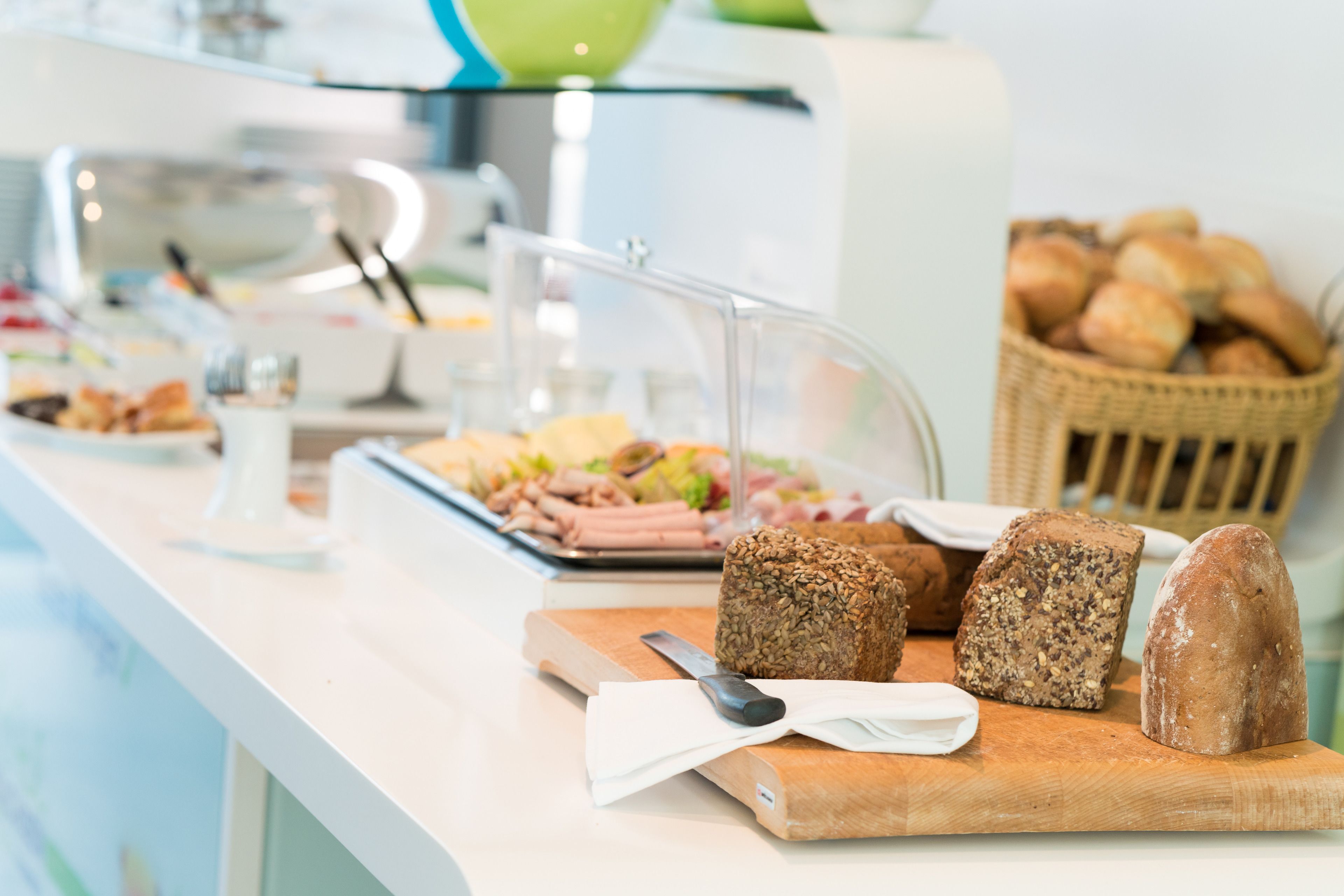 Une table de buffet avec divers aliments, notamment du pain, un couteau et une planche à découper.