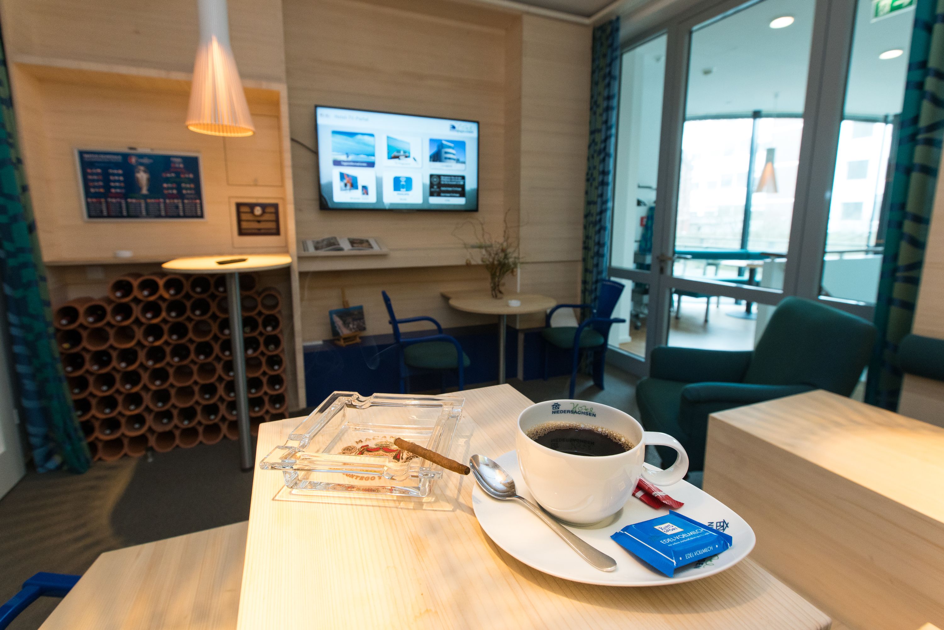 Een hotel receptie met een bijzettafeltje, een kop koffie, een sigaar en een menubord.