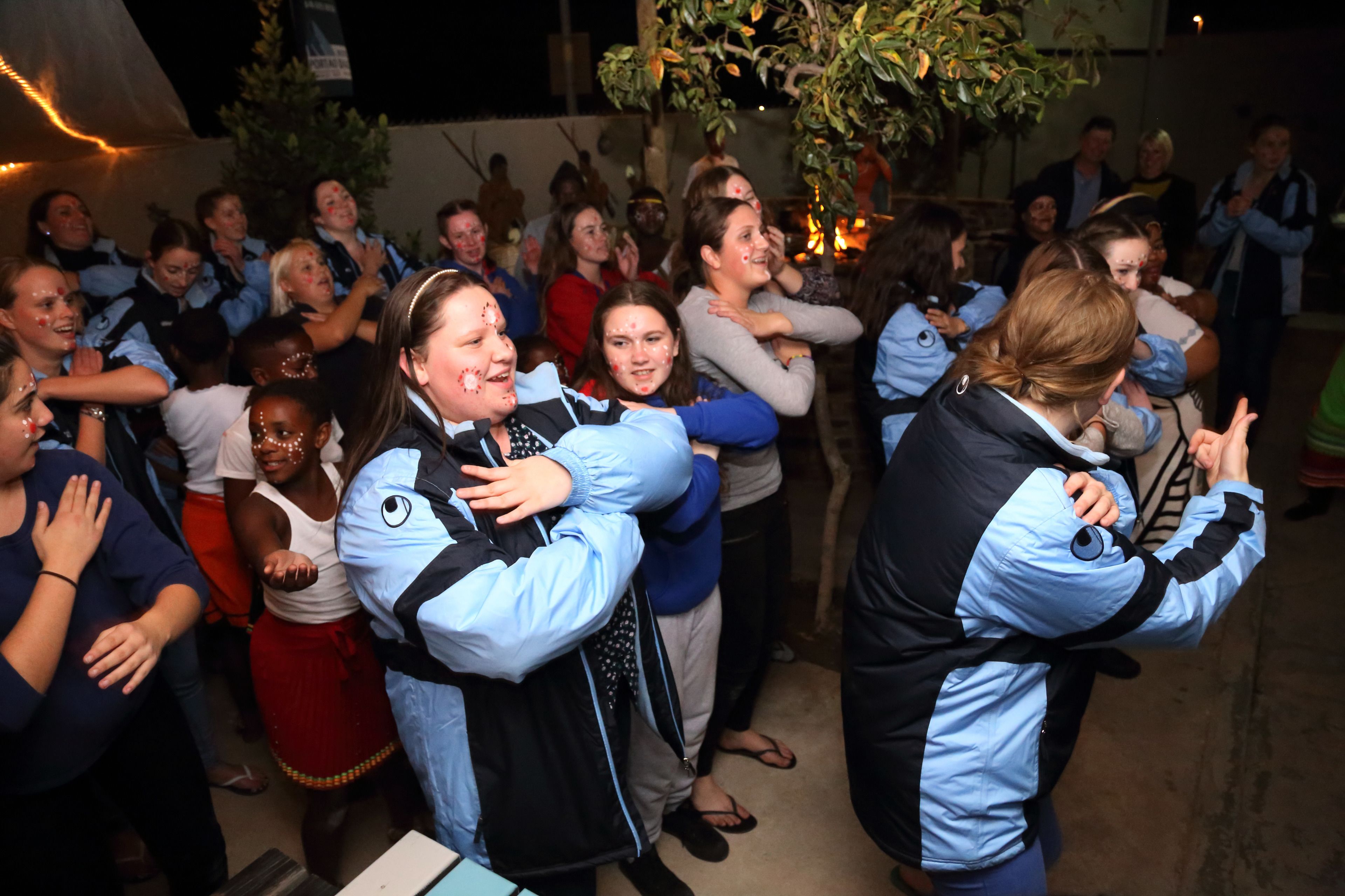 A group of people gathered indoors, some wearing jackets and others in casual attire.