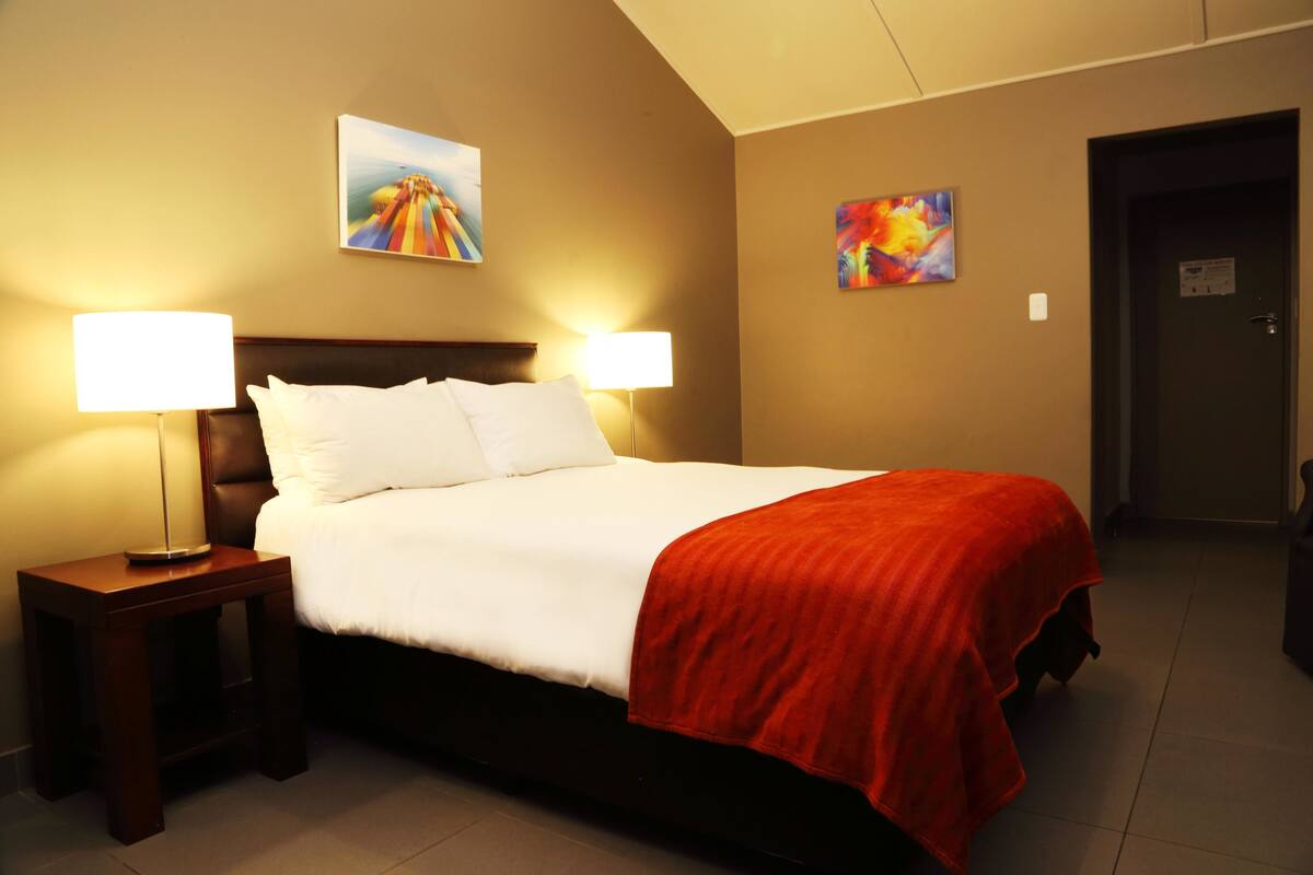 Ein Hotelzimmer mit einem großen Bett, zwei Nachttischlampen und zwei Bildern an den Wänden.