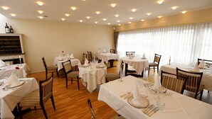 A dining area with multiple tables set for service, wooden flooring, and a wine rack in the background. - Slukefter Kro (Vojens)