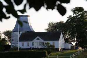 A white house with a distinctive conical roof, surrounded by greenery and a white fence. - Slukefter Kro (Vojens)