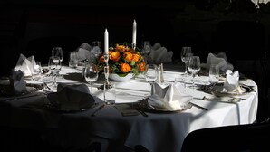 A table set for a formal dining event with white tablecloths, clear glassware, and a centerpiece of orange flowers. - Slukefter Kro (Vojens)