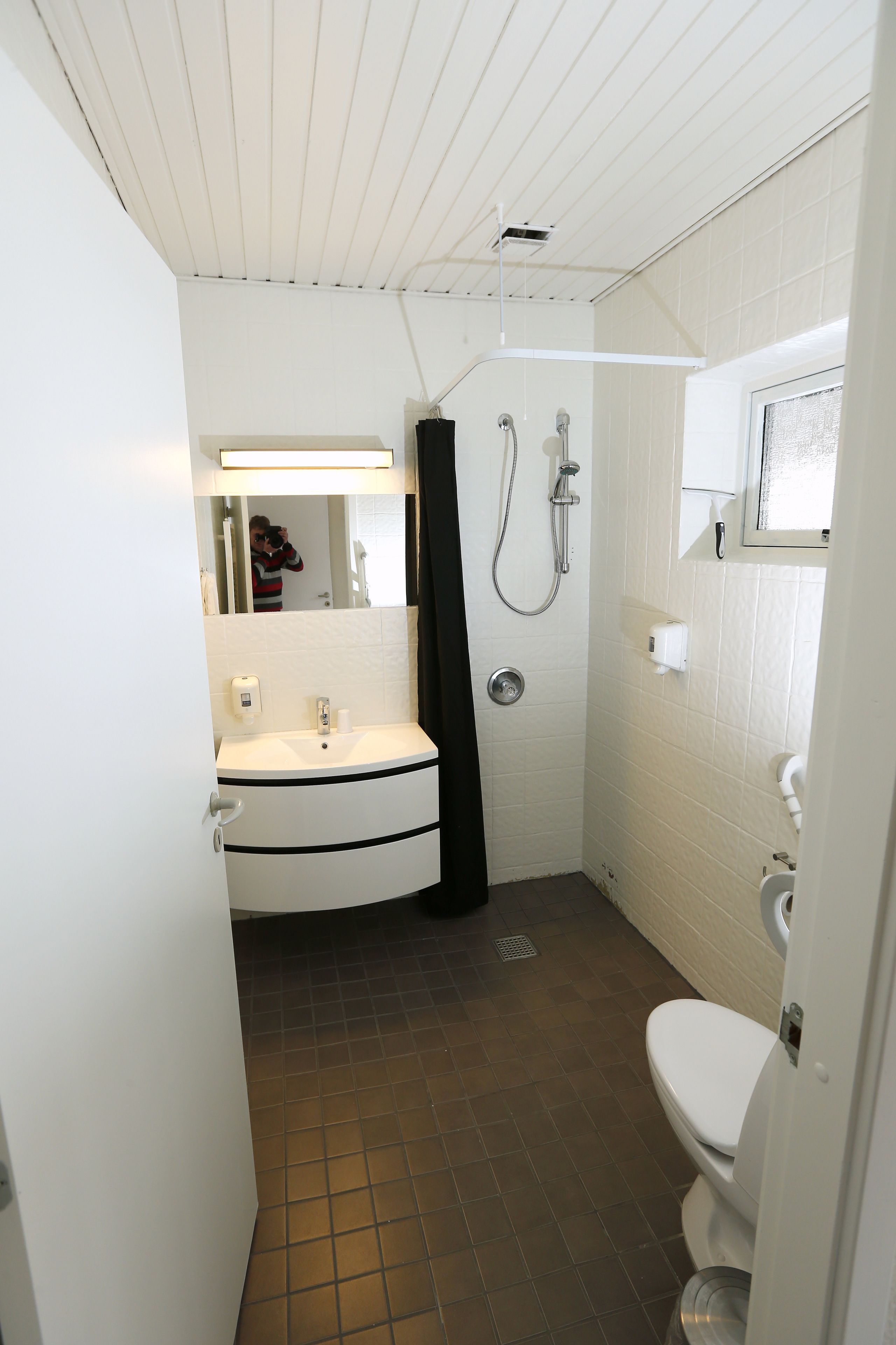 A compact bathroom with a sink, toilet, and shower.