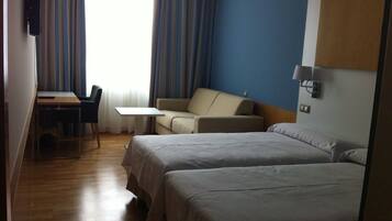 Una habitación de hotel con dos camas, un escritorio, una silla y un sofá.