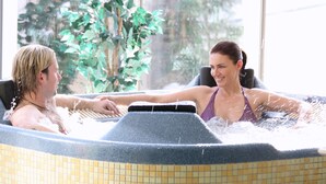 Een jacuzzi met betegelde wanden en uitzicht op groen.