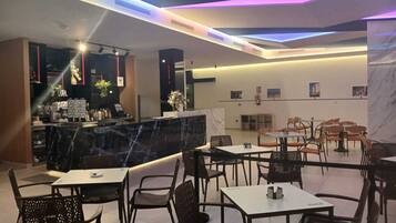 A modern restaurant with a bar area, seating, and a marble accent wall.