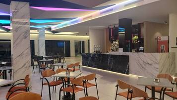 Un hall d’hôtel moderne, doté de colonnes en marbre, d’un comptoir d’accueil et d’espaces aménagés pour s’asseoir.