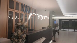 Un mostrador de recepción con diseño moderno, un amplio ventanal y una planta decorativa.