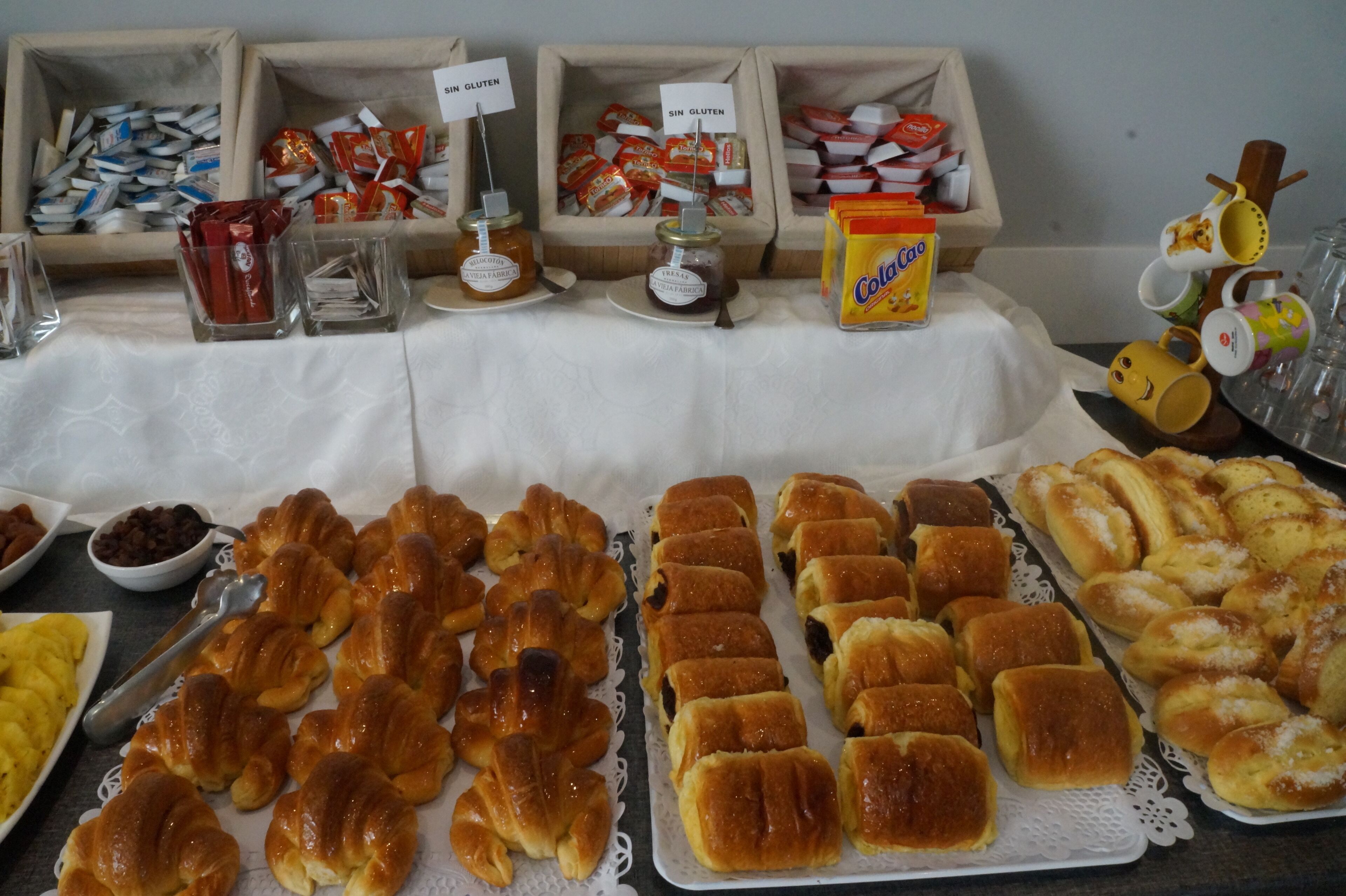 Una mesa de buffet con diferentes alimentos, incluyendo pasteles, pan y salsas.