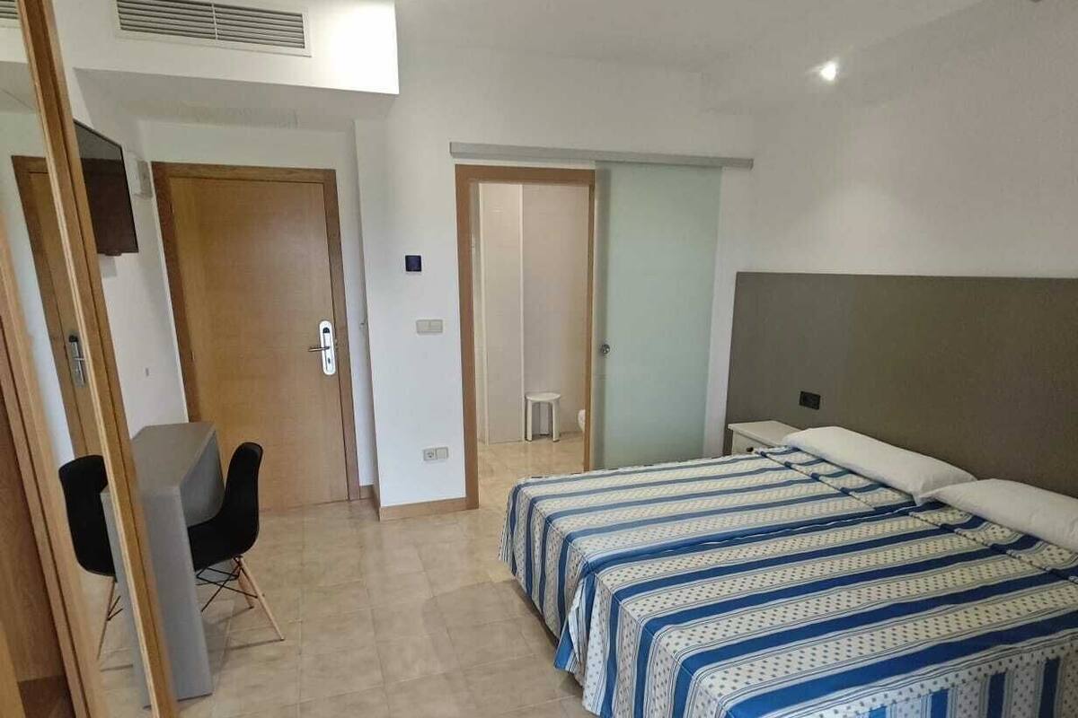A bedroom with a bed, a desk, and a chair.