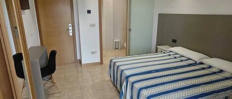 A bedroom with a bed, a desk, and a chair.