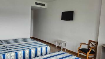 A room with two beds, a TV, a chair, and a small table.