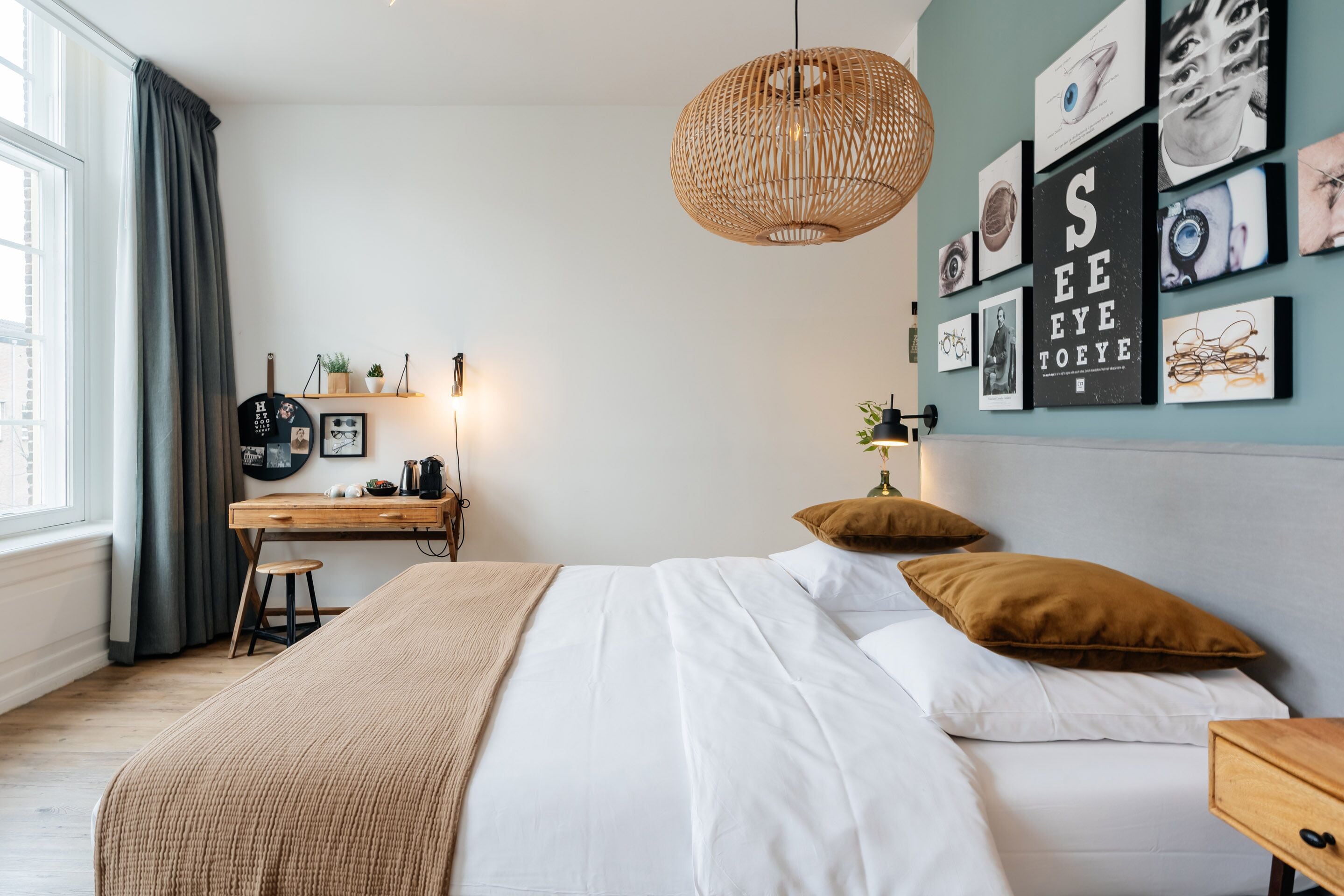 Un dormitorio con una cama, un escritorio y una pared con cuadros.