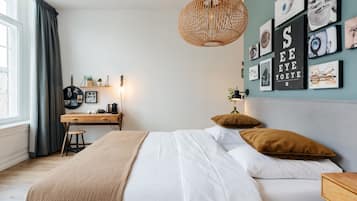 Un dormitorio con una cama, un escritorio y una pared con cuadros.