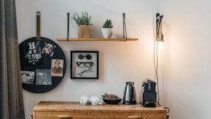 A wooden desk with a stool, a shelf with plants, a framed photo, and a coffee maker. - Eye Hotel (Utrecht)