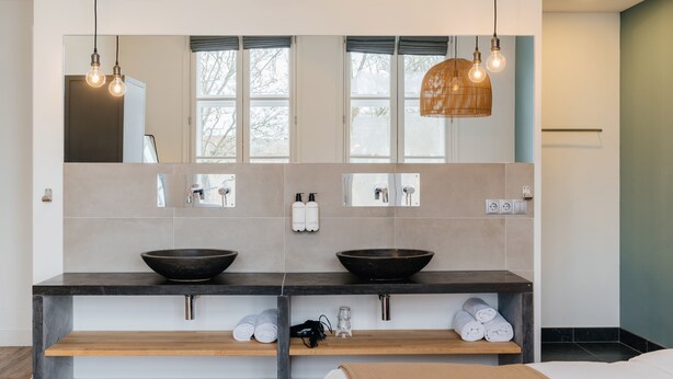 A modern bathroom with a double sink, large mirror, and two pendant lights. - Eye Hotel (Utrecht)