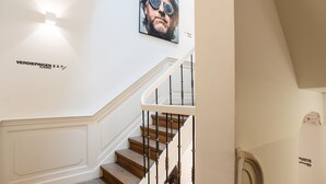 A staircase with wooden steps and white balustrades, a framed artwork above, and a sign indicating floors 2 and 3. - Eye Hotel (Utrecht)