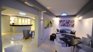 A modern hotel lobby with a reception desk, seating area, and a staircase. - Ialysos City Hotel (Rhodes)