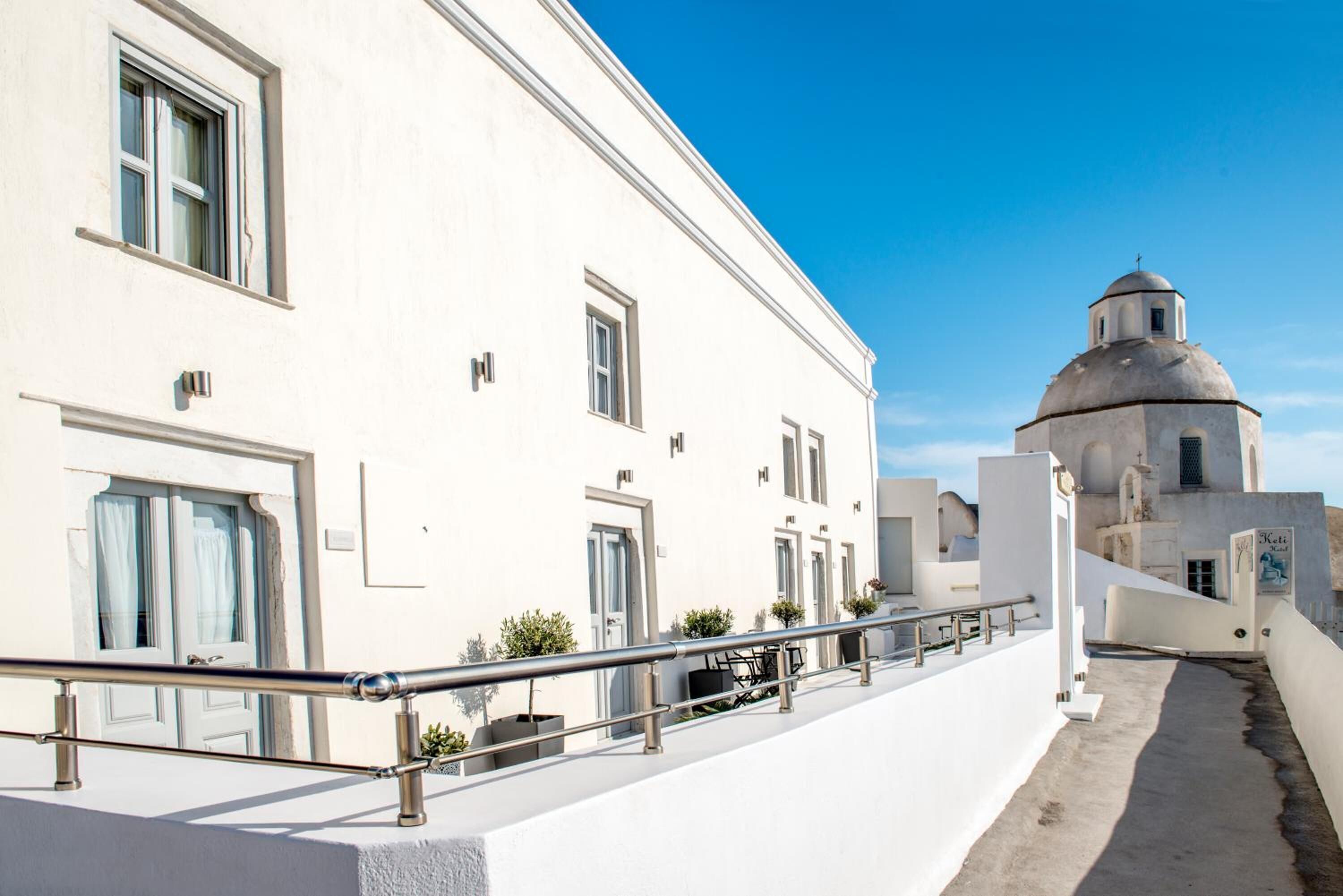 A white building with a dome and a balcony with a metal railing.
