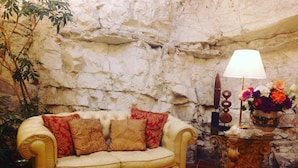 A room with a beige sofa, a lamp, and a vase of flowers. - Hotel La Rocca (Gubbio)