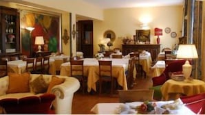 A hotel lobby with a dining area, a sofa, and a table with a lamp. - Hotel La Rocca (Gubbio)