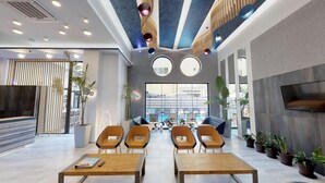 Um lobby moderno com vista para a piscina, mobiliário de madeira e plantas em vasos.