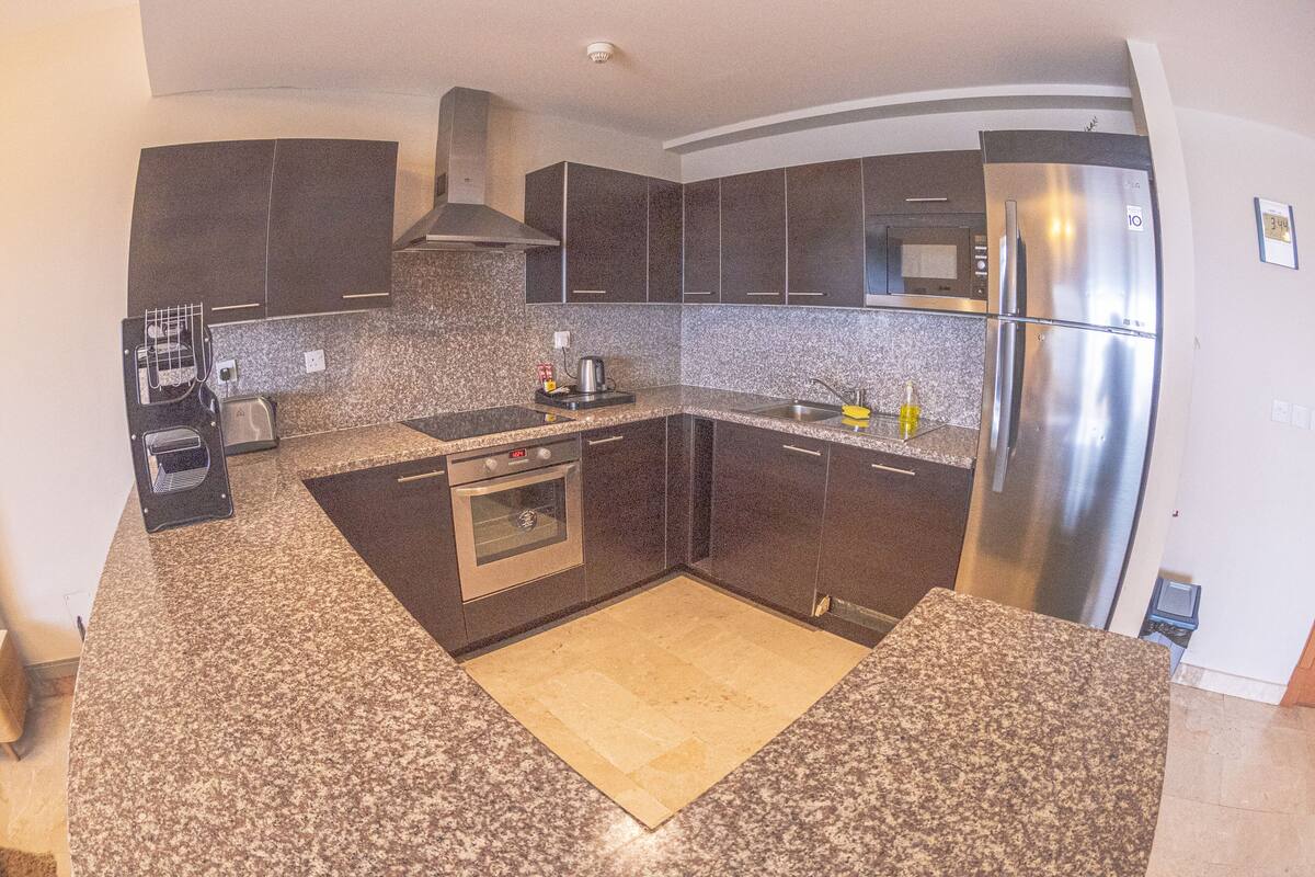 A modern kitchen with granite countertops, stainless steel appliances, and dark cabinetry.
