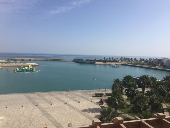 Uma marina costeira com barcos, uma praia de areia e palmeiras.