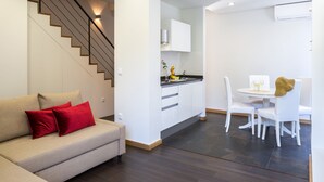 Una sala de estar moderna con un sofá, una escalera, una cocina y un comedor.