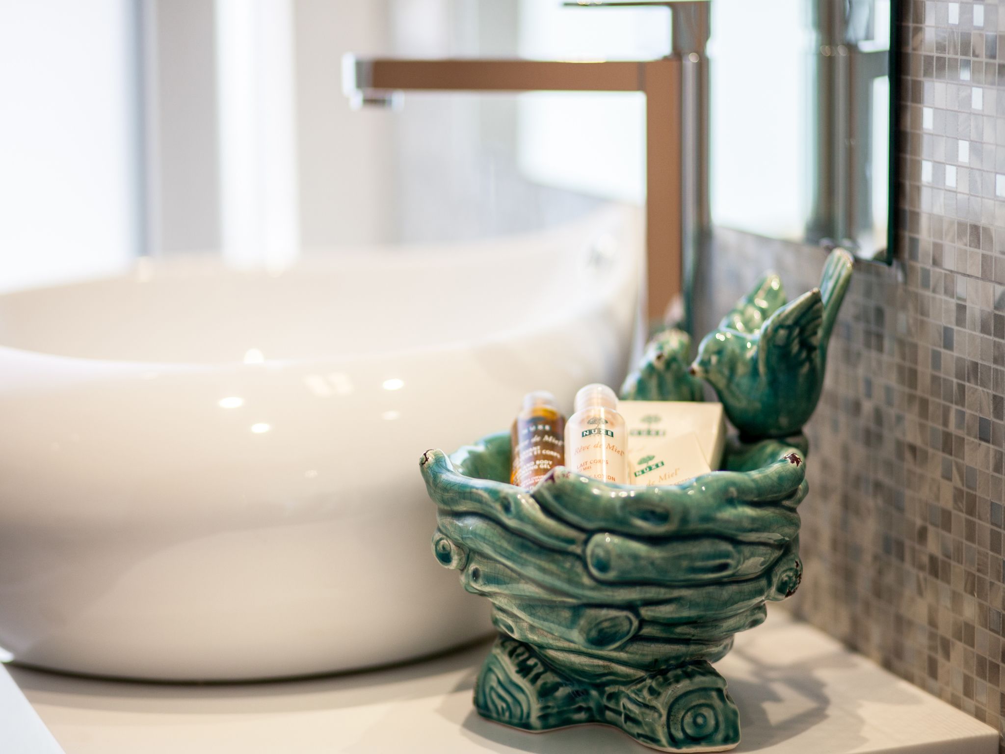 A bathroom sink with a green ceramic basin containing toiletries.