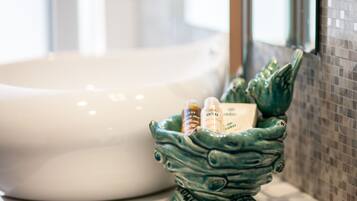 A bathroom sink with a green ceramic basin containing toiletries.
