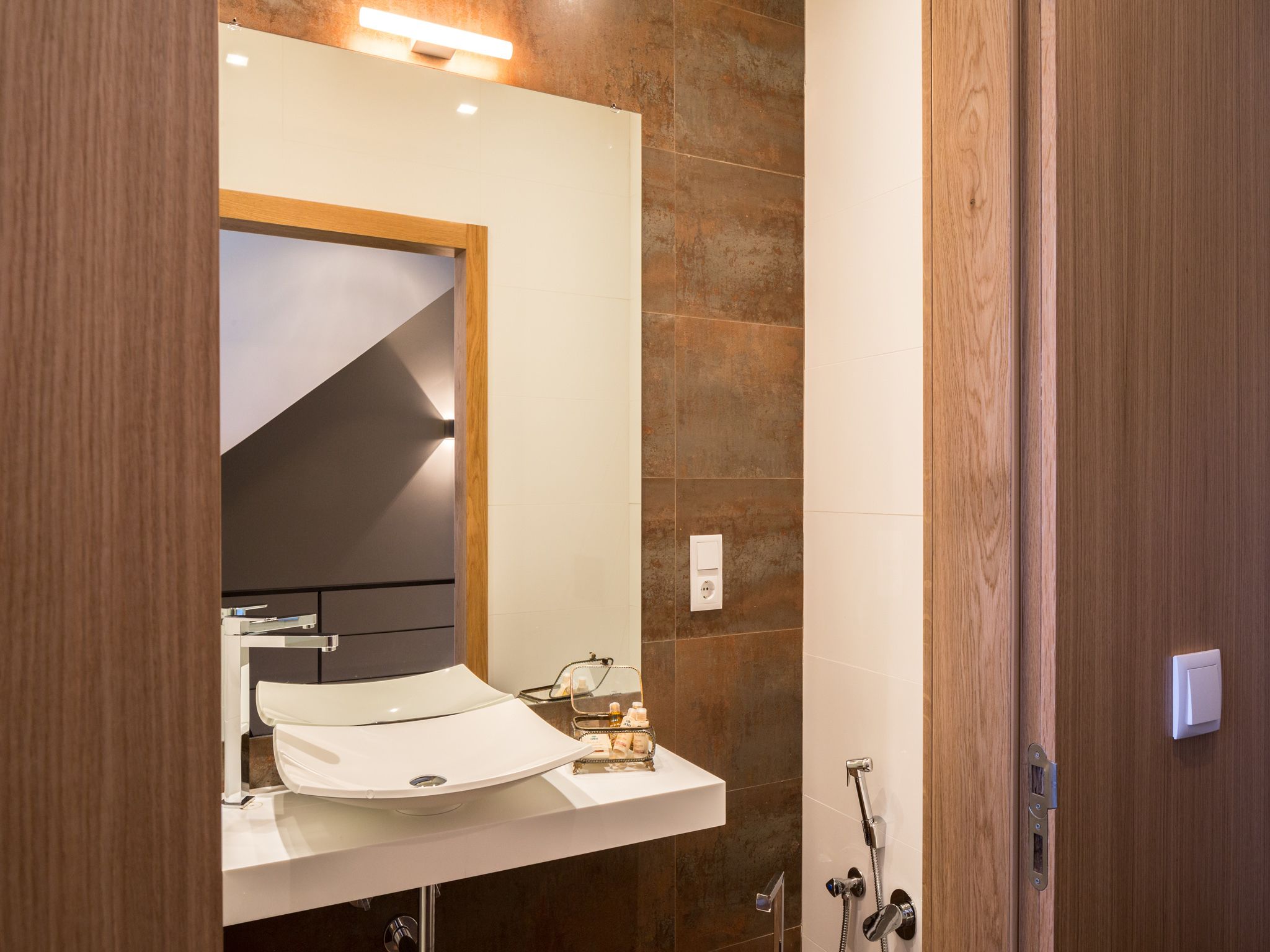 Un baño moderno con un lavamanos blanco, un espejo y una ducha.
