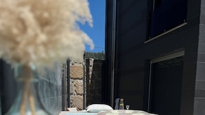 Un área de piscina moderna con una piscina azul cristalina, una silla de descanso y un muro de piedra.