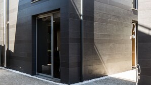 Un edificio moderno con fachada oscura, ventanas amplias y una entrada visible.