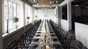 A long dining table with chairs, set for a meal, in a room with wooden beams and hanging light fixtures. - Hotel Skjern (Skjern)