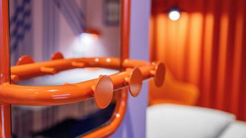 Detailaufnahme einer gewölbten, orangefarbenen Metallstruktur mit runden Elementen, vermutlich ein Teil der Innenraumgestaltung eines Raumes.