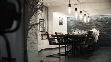 A modern dining area with a long table, leather chairs, and pendant lighting.