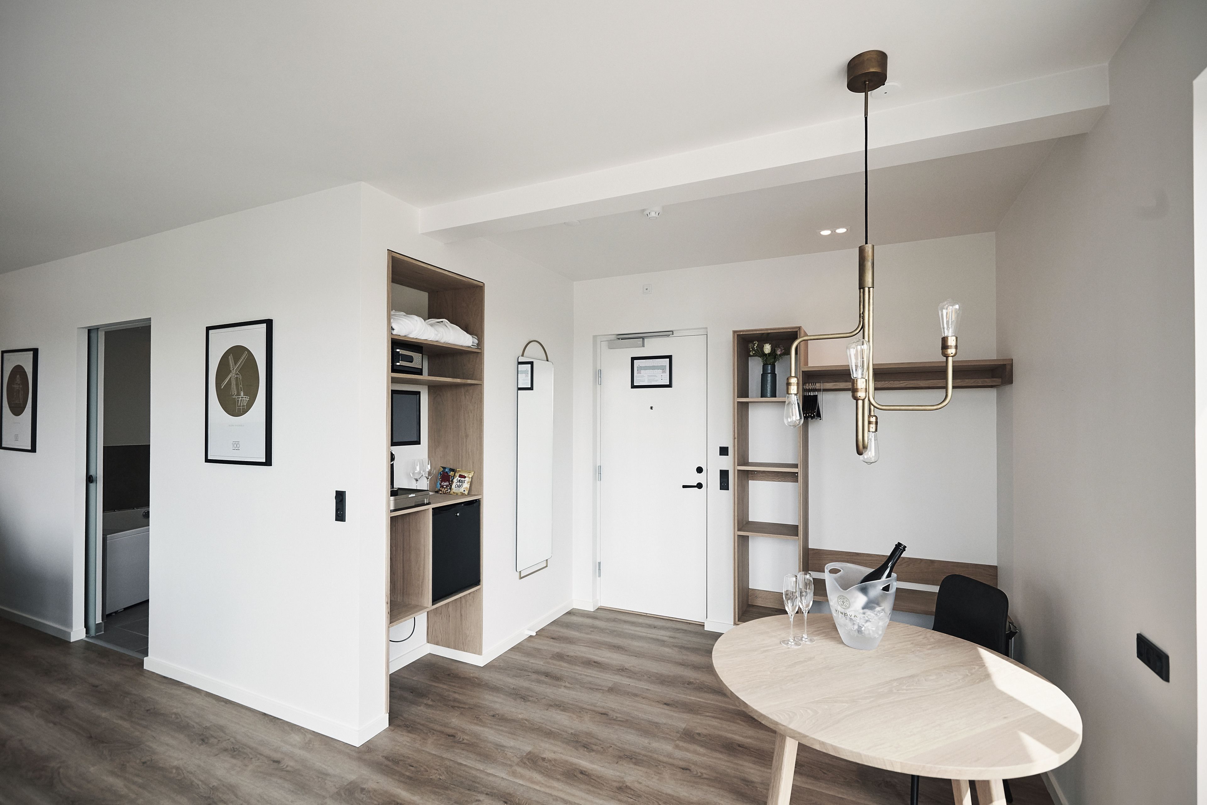A modern, well-lit room with a dining table, a chandelier, and a wardrobe.